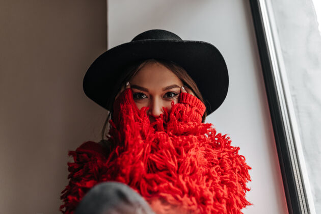 房间坐在窗台上的一位穿着红毛衣 戴着黑宽边帽的惊艳女子可爱魅力时尚