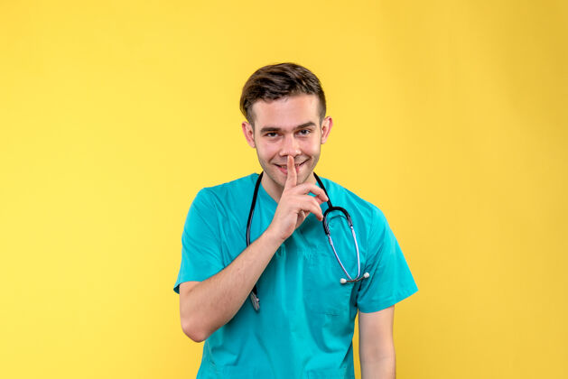 仪器黄色墙上微笑的年轻男医生的正面图人病毒设备