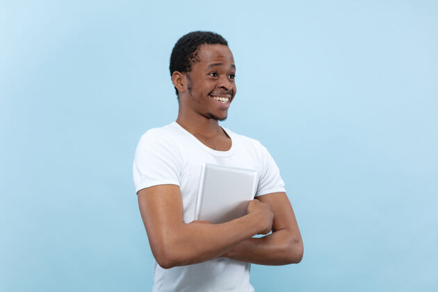 就业在蓝色空间里 一位身穿白衬衫的非洲裔美国年轻人的半身特写肖像手持平板电脑 面带微笑工作成功男人