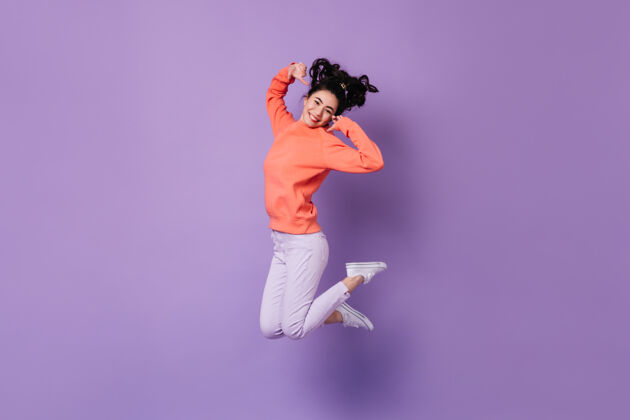 女士快乐的日本女人在紫色的背景上跳跃幸福的亚洲年轻女子的摄影棚拍摄年轻狂喜快乐