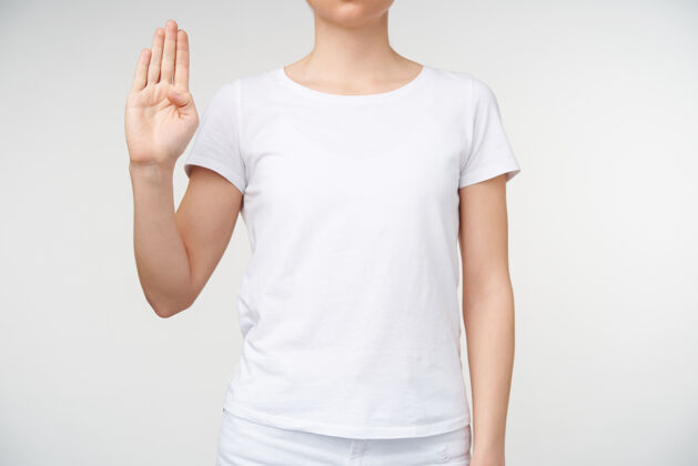 翻译照片中的年轻女子学习聋哑字母和形成字母b与提高的手 被隔离在白色背景白色基本t恤沟通休闲成人
