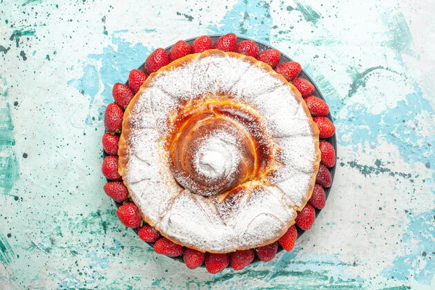 顶部顶视图糖粉蛋糕与新鲜的红色草莓淡蓝色的表面粉末草莓图案