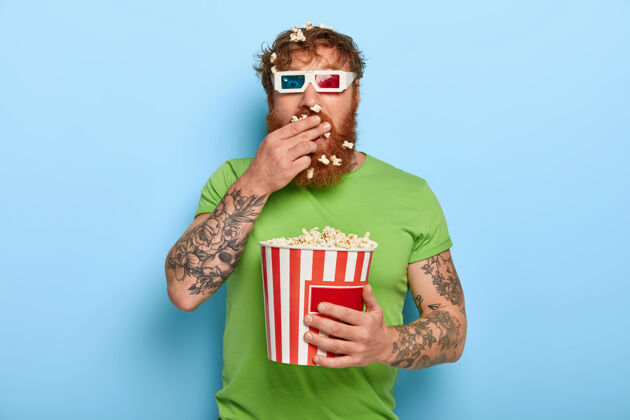 红发一个迷人的红发男人透过电影院的眼镜凝视着镜头T恤观众男性