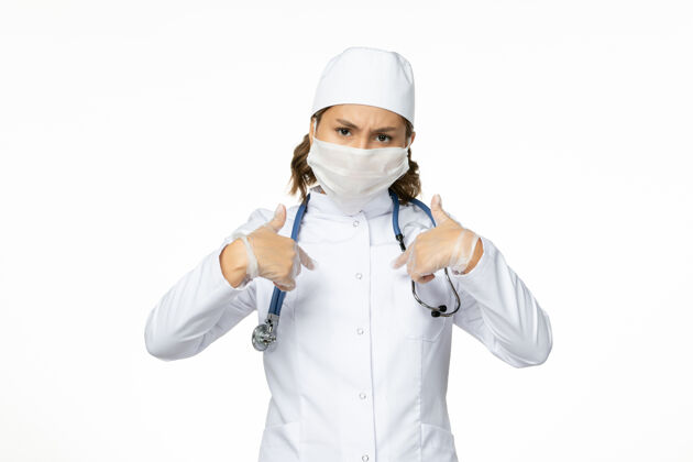 口罩正面图年轻女医生带着无菌口罩和手套由于冠状病毒在浅白的表面灭菌冠状病毒到期