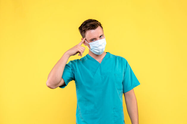 医院黄墙上戴着无菌口罩的男医生的正视图医学男医生帅哥