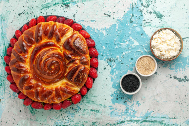 蛋糕俯瞰圆形美味的烤馅饼和蓝色表面草莓甜蛋糕面团生的糖