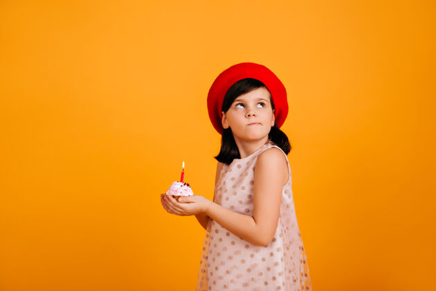 女性小女孩许生日愿望深色头发的小孩拿着蛋糕 黄色的墙上挂着蜡烛女孩时尚乐趣