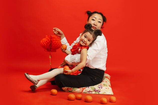 旗袍拥抱 微笑 快乐 手持灯笼2020年中国新年快乐传统服装红色背景上的亚洲母女肖像家庭手新年