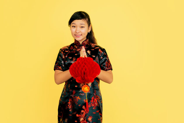 传统带着灯笼 微笑着 谢谢中国新年快乐黄色背景上的亚洲少女肖像身着传统服装的女模特看起来很快乐复制空间服装中国女性