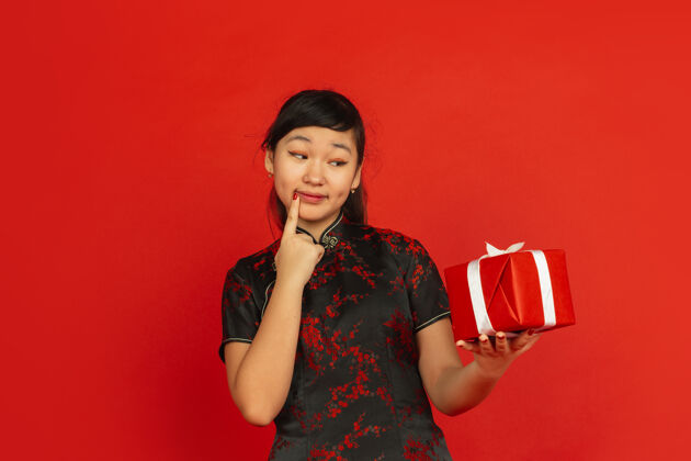 装饰猜猜看礼物是什么中国新年快乐红色背景上孤立的亚洲女孩肖像穿着传统服装的女模特看起来很快乐庆祝 节日 情感复制空间服装欢乐节日