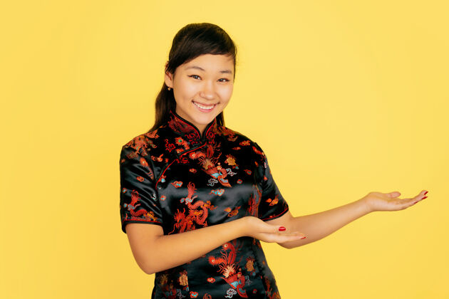 手微笑可爱 展现在身边中国新年快乐黄色背景上的亚洲少女肖像身着传统服装的女模特看起来很快乐庆祝 人类情感复制空间祝福年中国