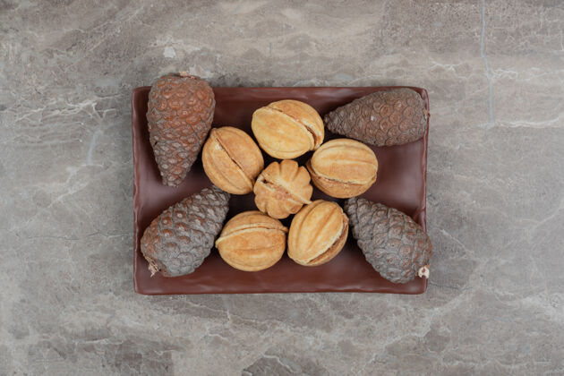 饼干核桃形状的饼干和松果放在深色的盘子里高质量的照片坚果焦糖面包房