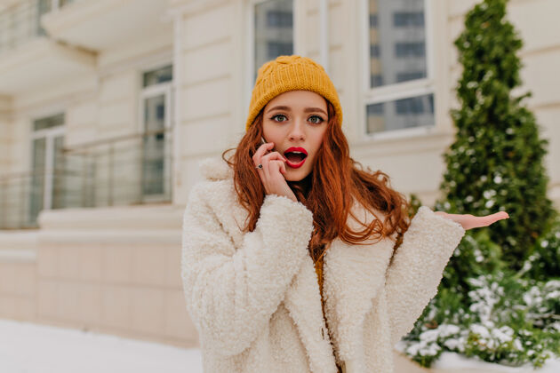 户外在寒冷的日子里 一位迷人的女士 一头深色的卷发在打电话令人惊叹的姜汁女孩的冬季肖像外套肖像雪