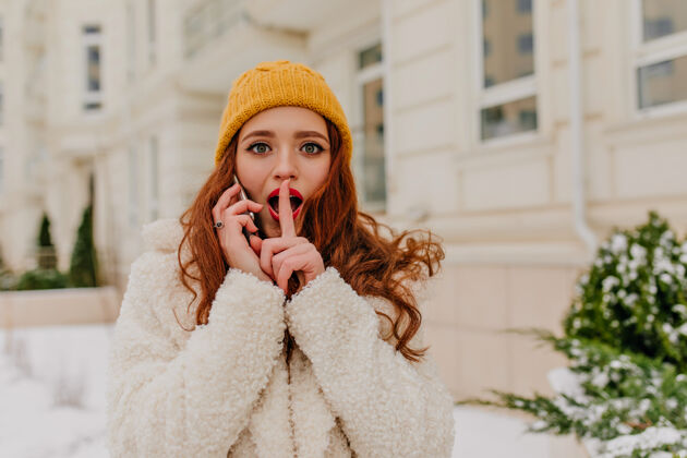 外套好奇的红发女孩戴着帽子在户外打电话漂亮的年轻女人在打电话给别人乐趣欢呼寒冷