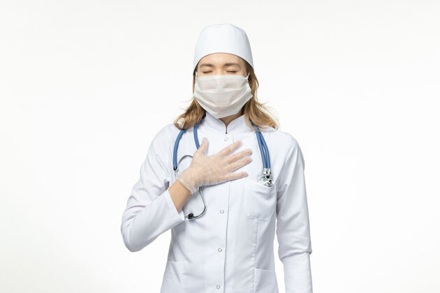 口罩正面图身穿医疗服的年轻女医生戴着防护面罩 白色地板上有冠状病毒听诊器大流行疾病