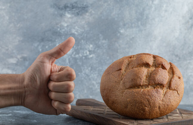 面包男子向黑麦面包伸出大拇指高质量照片板好老
