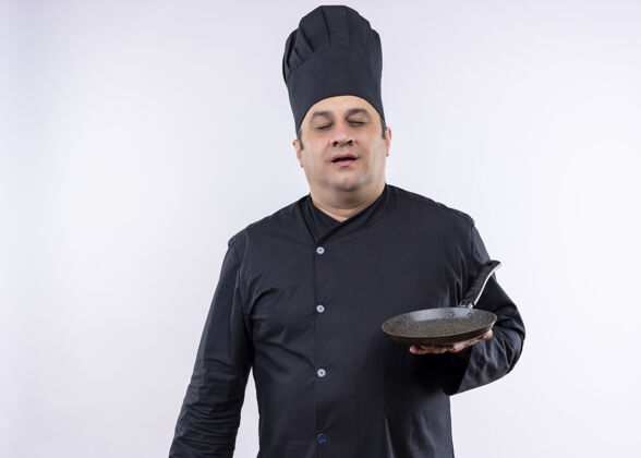 黑男厨师身穿黑色制服 头戴厨师帽 举着平底锅 闭着眼睛站在白色背景上制服立场封闭
