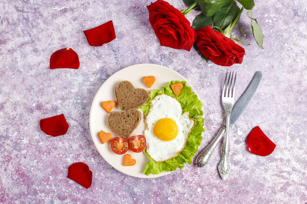 美食情人节早餐-炸鸡蛋 心形面包和新鲜蔬菜情人节烹饪餐桌