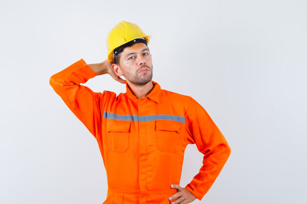 工业年轻工人穿着制服 戴着头盔 手放在脑后 看上去很优雅优雅人团队合作