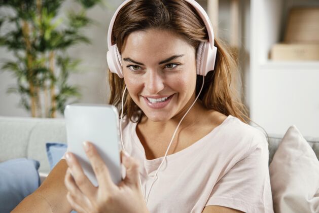 女人戴着耳机的女人用手机笑脸手机设备