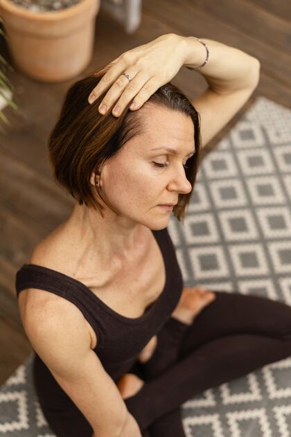 活跃中等身材的女人在室内冥想练习女士瑜伽