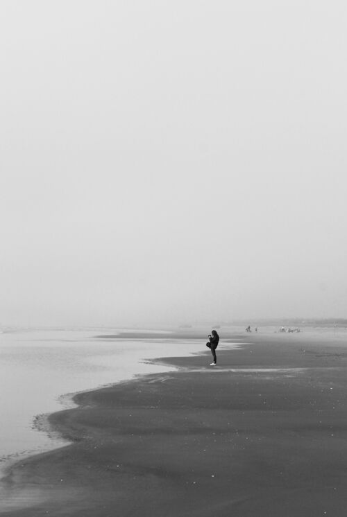 海一个孤独的人在黑云下走在沙滩上的灰度照片云天空海岸