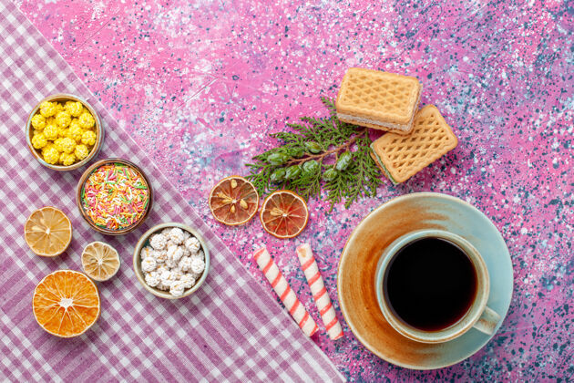 在粉红色的桌子上放一杯茶和饼干 华夫饼和糖果杯子食品桌子