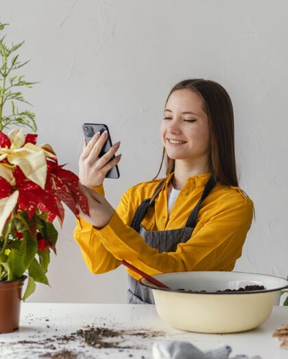 花园正在给她的植物拍照的年轻女人室内植物栽培植物