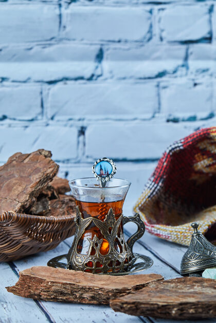 勺子红茶放在传统的玻璃杯子里 饼干放在蓝色的木桌上芳香茶木头