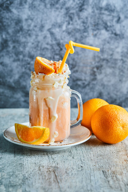 鸡尾酒在白色盘子上撒上糖和稻草的橙色冰沙杯子鞭子柑橘