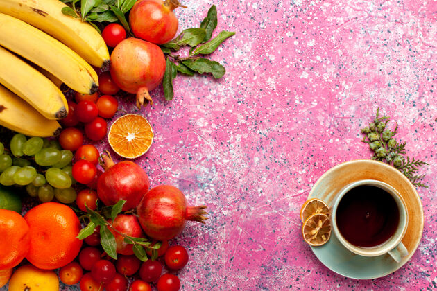 顶部顶视图新鲜水果组成的茶杯浅粉红色的桌子上茶西红柿杯子