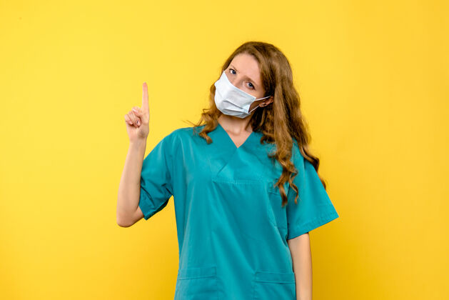 面具黄色空间里戴着面具的女医生的正视图自信人病毒