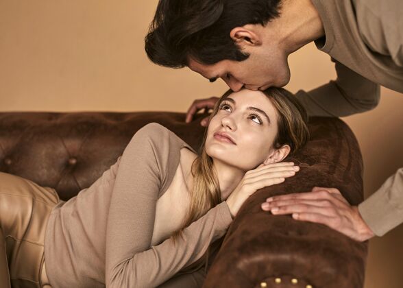 亲吻坐在沙发上的男人亲吻女人额头的侧视图丈夫情侣封闭