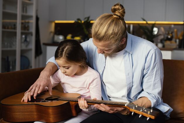 女孩小女孩和爸爸一起弹吉他的正面图吉他父母国际