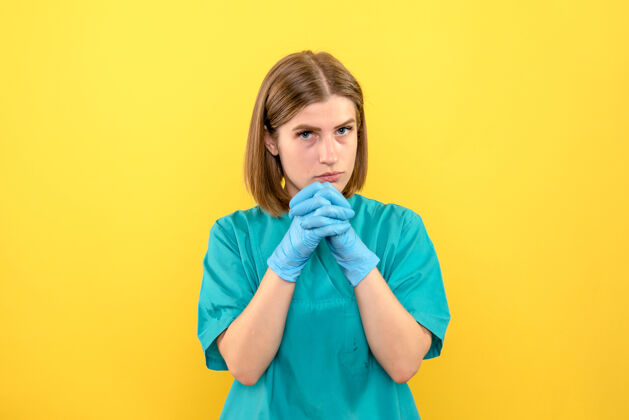 医院前视图黄色空间上戴着蓝色手套的女医生成人视图穿着