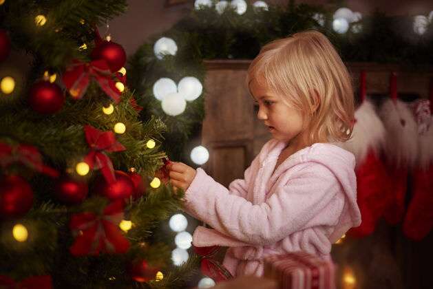 魔术小女孩在装饰圣诞树庆祝蝴蝶结客厅