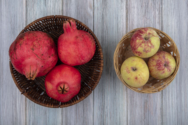 灰色新鲜多汁和红润的石榴桶与苹果桶上的灰色背景俯视图水果苹果新鲜