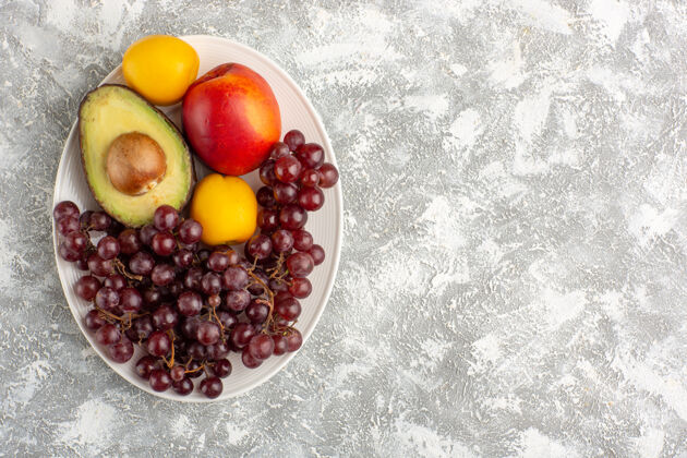 鳄梨顶视图新鲜水果 葡萄 桃子和鳄梨在白色的盘子里新鲜水果可食用水果