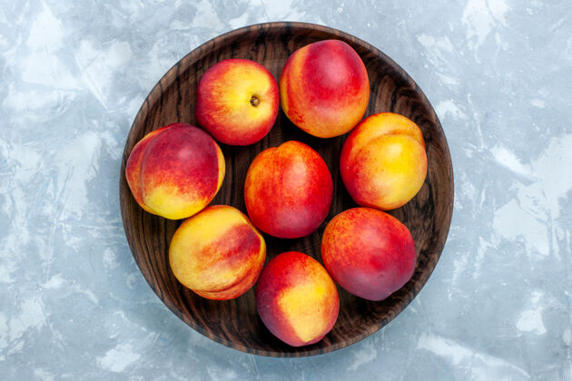 水果顶视图新鲜桃子醇厚可口的水果内棕色盘子在浅白色的办公桌上顶部甜的新鲜的