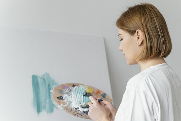 女性美丽的女人在画布上用丙烯酸树脂绘画室内房子油漆
