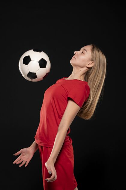 年轻侧视图：一个和切斯特一起踢足球的女人足球制服女侧视图