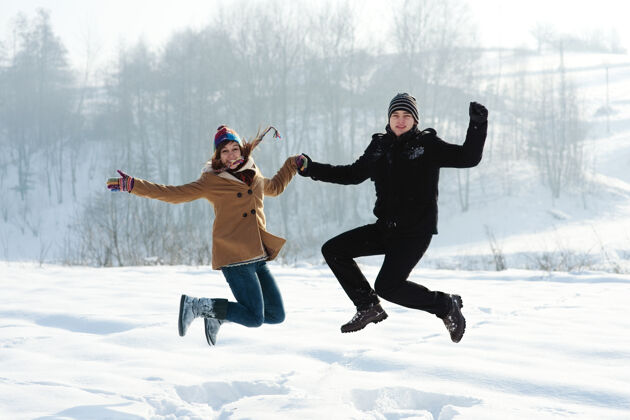 牛仔裤冬天的乐趣 年轻的夫妇跳户外跳跃自然寒冷