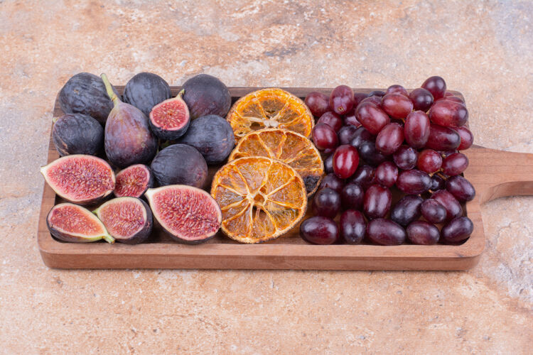 清淡紫色无花果与干燥的橙色切片和山茱萸浆果在木板上健康蔬菜产品