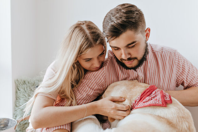 女性可爱的丈夫和妻子在浪漫的心情与爱看他们的拉布拉多女孩抚摸他的狗和拥抱的男朋友团聚男朋友狗