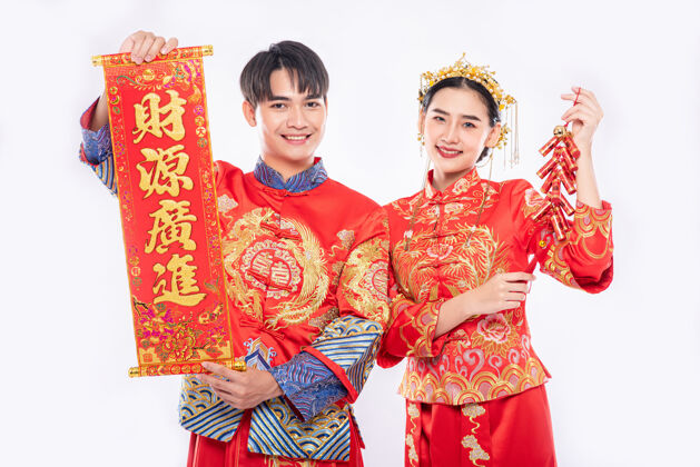 女孩中国的贺卡和鞭炮是男人和女人穿旗袍套装在中国新年庆祝使用成人人中国文化