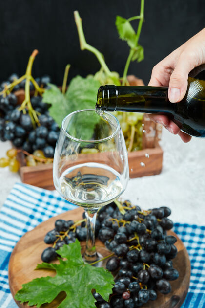 自然把葡萄酒倒进杯子里 把一盘葡萄放在白色的桌子上手吃的杯子