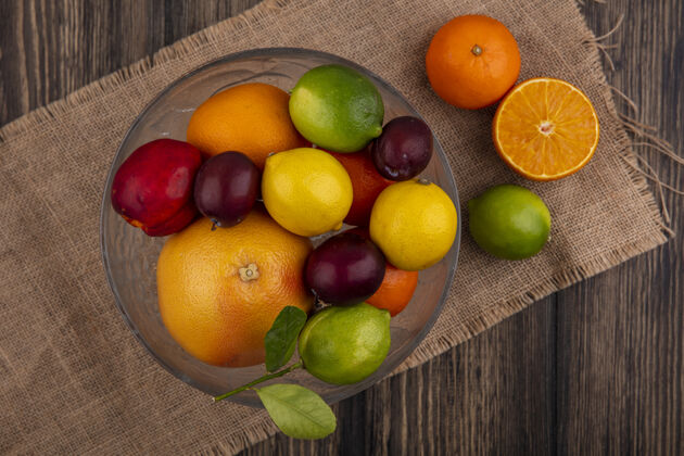 混合在米色餐巾纸上的花瓶里 可以看到水果 柠檬 酸橙 李子 桃子和橙子的组合米色橙色食物