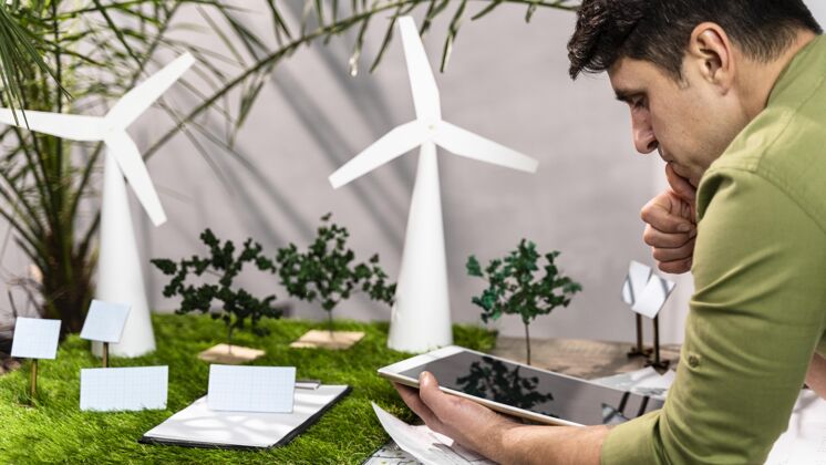 环保人类使用平板电脑旁边的生态友好型风力发电项目布局侧视图项目环保环保