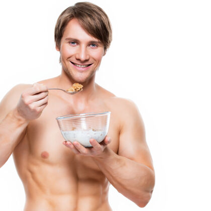 肌肉一个年轻迷人的肌肉男吃牛奶片的肖像-隔离在白墙上年轻胡须没刮胡子