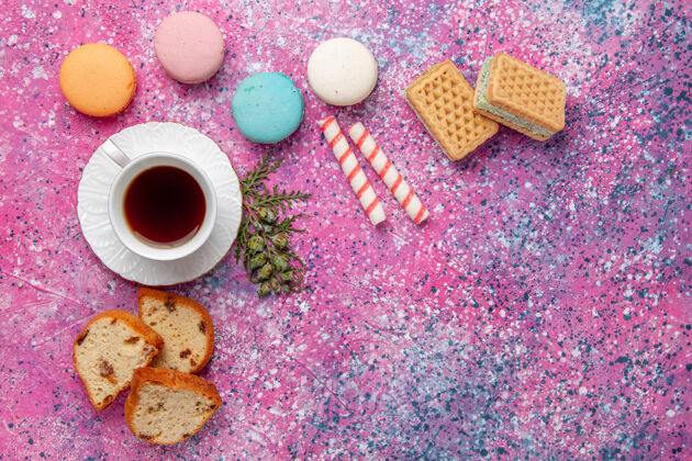 糖顶视图一杯茶 配上五颜六色的法国马卡龙和华夫饼 粉色墙壁蛋糕饼干糖甜饼茶咖啡五颜六色茶